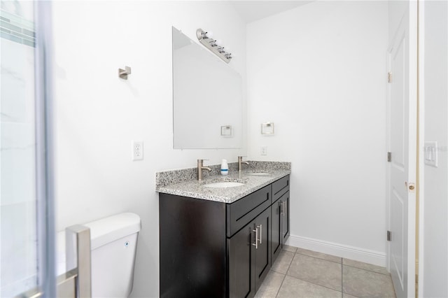 bathroom with a sink, toilet, double vanity, and tile patterned flooring