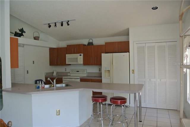 kitchen with brown cabinetry, white appliances, light countertops, and a sink