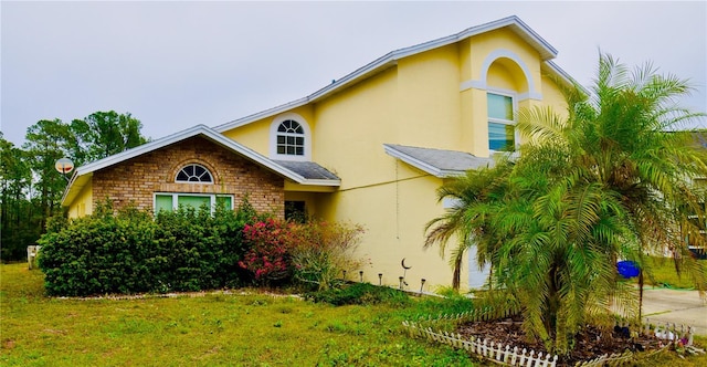 view of front of property with brick siding, a front lawn, and stucco siding