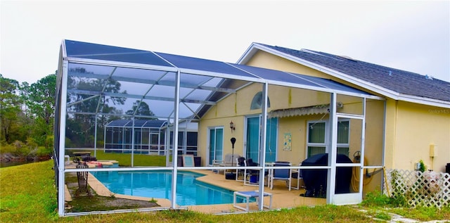 back of property with a patio, stucco siding, a shingled roof, a lanai, and an outdoor pool