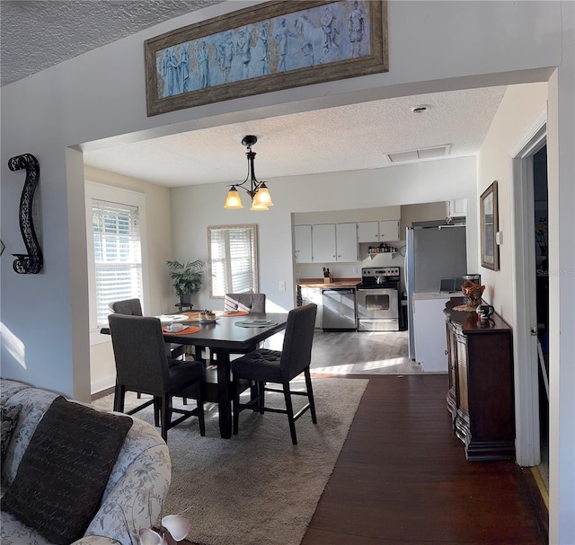 dining room with a textured ceiling, visible vents, and dark wood-style flooring