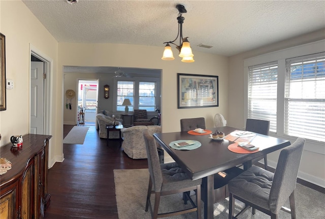 dining room with baseboards, a textured ceiling, a chandelier, and dark wood-type flooring