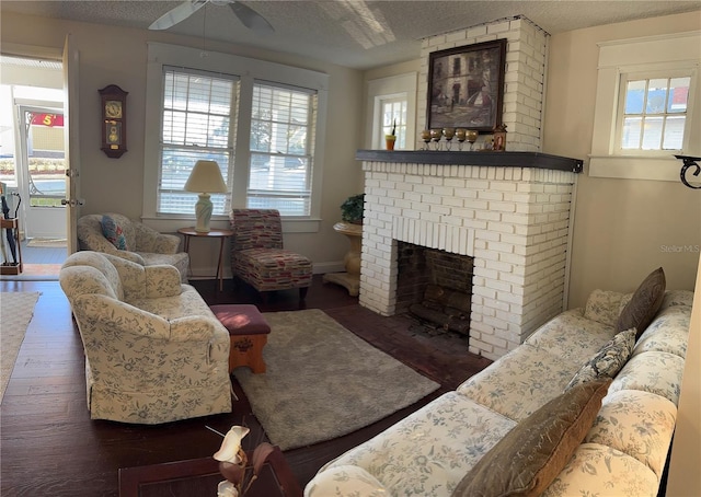 living area with a healthy amount of sunlight, a brick fireplace, dark wood-style flooring, and a textured ceiling