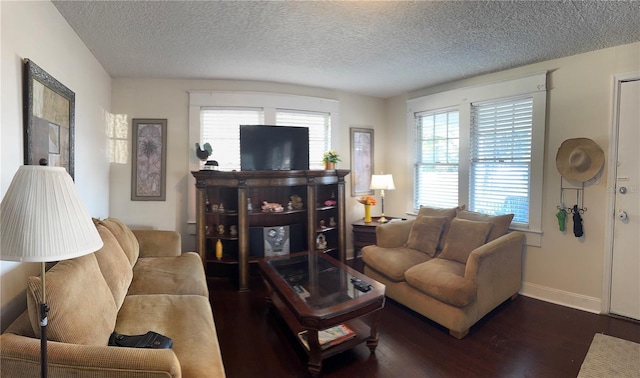 living room featuring a textured ceiling, dark wood-type flooring, and baseboards