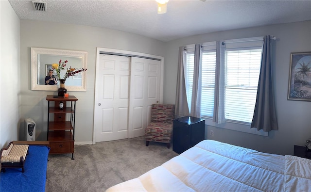 bedroom with a textured ceiling, a closet, carpet, and visible vents