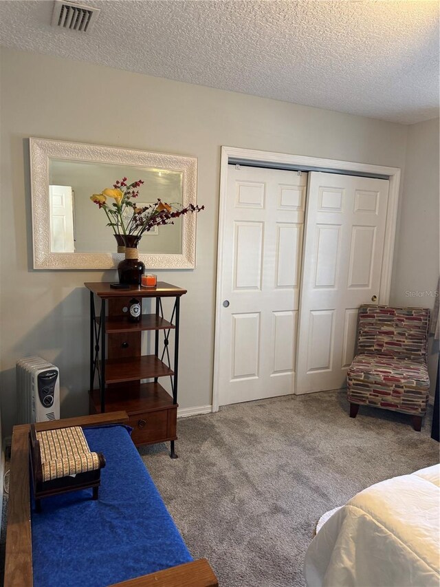 bedroom with carpet, a closet, visible vents, a textured ceiling, and baseboards