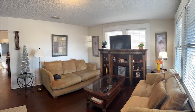 living area featuring dark wood finished floors, a textured ceiling, and baseboards