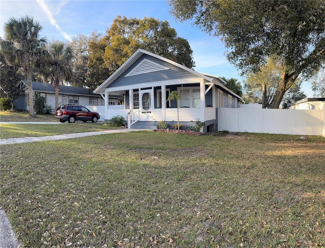 bungalow featuring a front lawn and fence