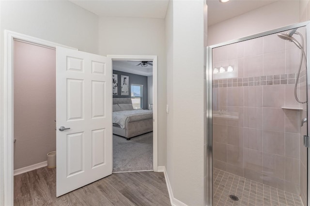 ensuite bathroom with a stall shower, wood finished floors, and baseboards