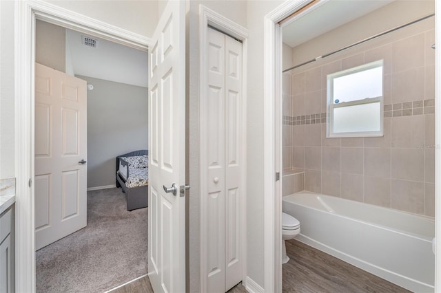 bathroom featuring toilet, vanity, shower / bath combination, and a closet
