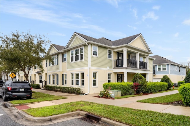 multi unit property featuring a residential view, a balcony, and a front yard