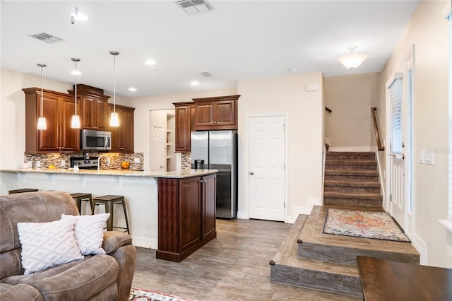 kitchen with a peninsula, visible vents, open floor plan, appliances with stainless steel finishes, and decorative light fixtures