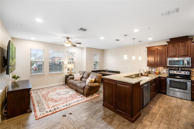 kitchen with stainless steel appliances, open floor plan, pendant lighting, and visible vents