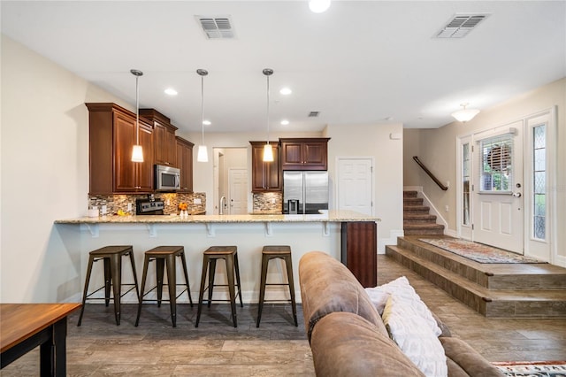 kitchen with stainless steel appliances, decorative light fixtures, visible vents, and a peninsula