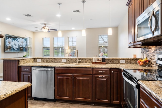 kitchen featuring decorative light fixtures, tasteful backsplash, visible vents, appliances with stainless steel finishes, and a sink