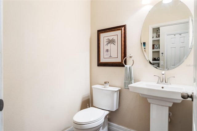 bathroom featuring toilet, baseboards, and a sink