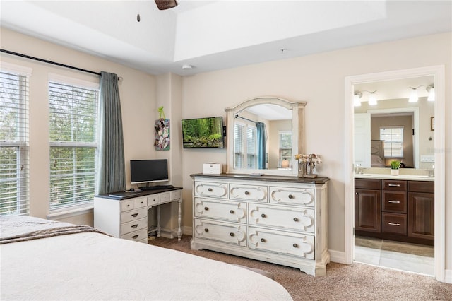 bedroom featuring light carpet, multiple windows, a sink, and ensuite bath