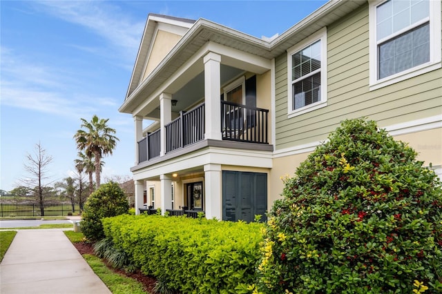 view of side of home featuring fence, a balcony, and stucco siding