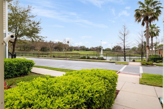 view of sport court with a water view and fence