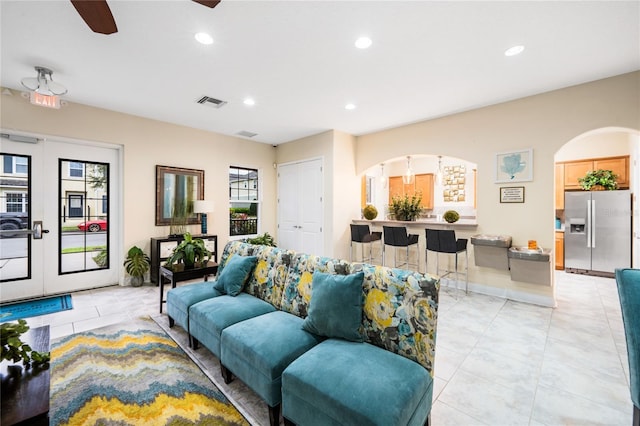 living room featuring arched walkways, visible vents, and recessed lighting