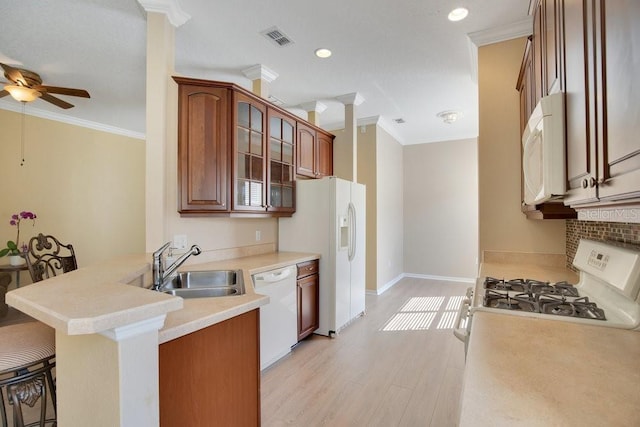 kitchen with white appliances, visible vents, light countertops, a kitchen bar, and glass insert cabinets