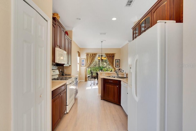 kitchen featuring white appliances, a sink, visible vents, light countertops, and glass insert cabinets