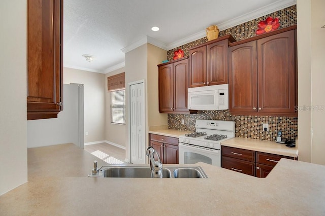 kitchen featuring white appliances, tasteful backsplash, ornamental molding, light countertops, and a sink