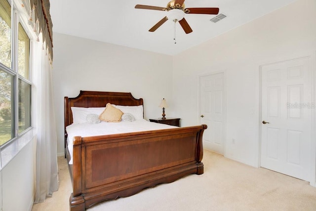 bedroom with light carpet, visible vents, and a ceiling fan