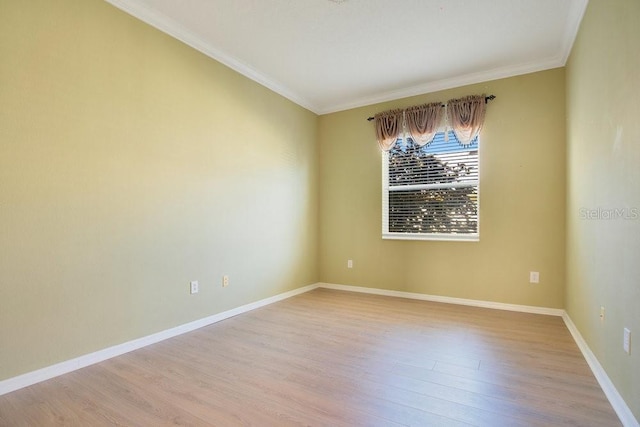 empty room featuring ornamental molding, baseboards, and light wood finished floors