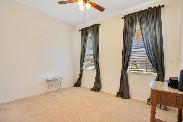 empty room featuring light carpet, a ceiling fan, and baseboards