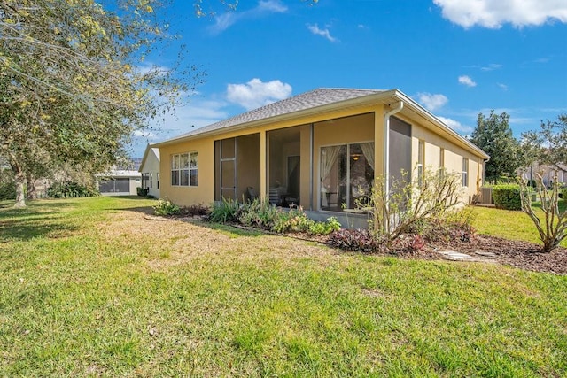 rear view of property with a yard, central AC unit, a sunroom, and stucco siding