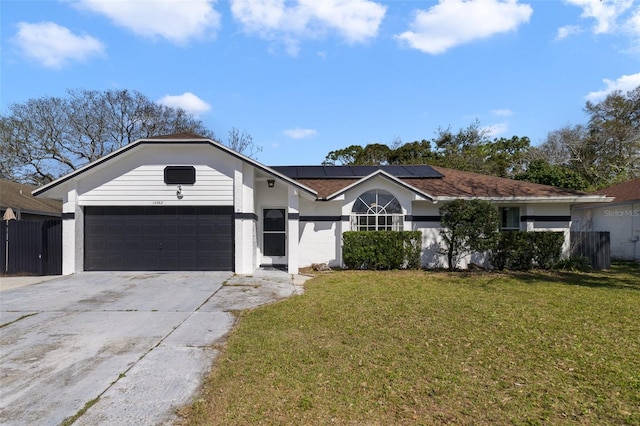 single story home featuring a front yard, roof mounted solar panels, driveway, and an attached garage