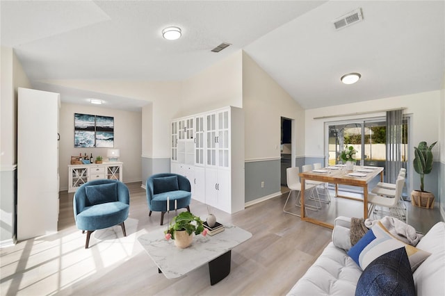 living area featuring visible vents, vaulted ceiling, a dry bar, and wood finished floors