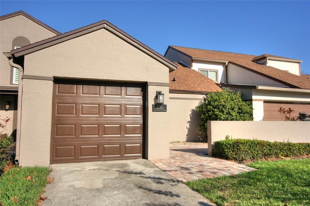 view of front of house featuring a shingled roof, an attached garage, and stucco siding