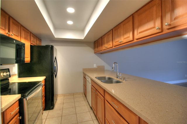 kitchen with electric range, brown cabinetry, a tray ceiling, black microwave, and a sink