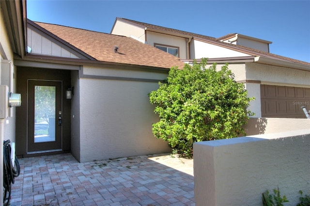 exterior space featuring roof with shingles and stucco siding