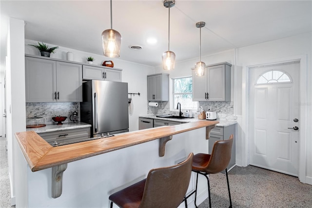 kitchen featuring visible vents, a kitchen breakfast bar, gray cabinets, stainless steel appliances, and a sink