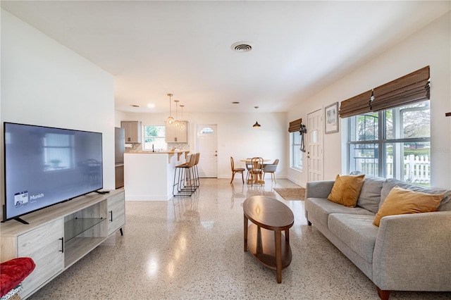 living room featuring baseboards, visible vents, and light speckled floor