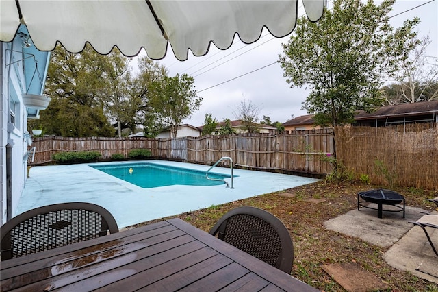 view of swimming pool featuring a fenced backyard, a fire pit, a fenced in pool, outdoor dining space, and a patio area