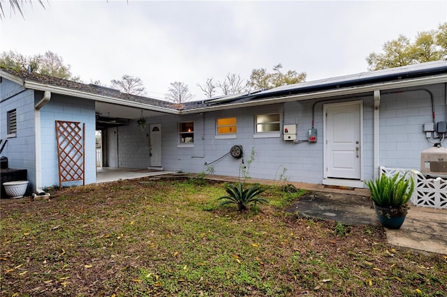 view of front of house featuring roof mounted solar panels, concrete block siding, and a patio