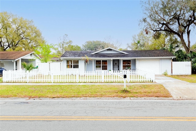 view of front of home with a fenced front yard, a front yard, concrete driveway, and a garage