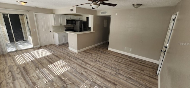 kitchen featuring visible vents, stainless steel microwave, stove, freestanding refrigerator, and light countertops