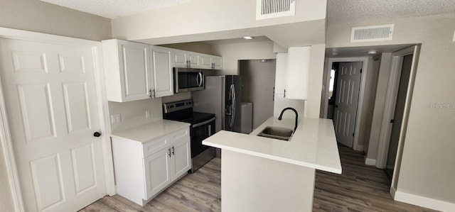 kitchen featuring visible vents, appliances with stainless steel finishes, light countertops, white cabinetry, and a sink