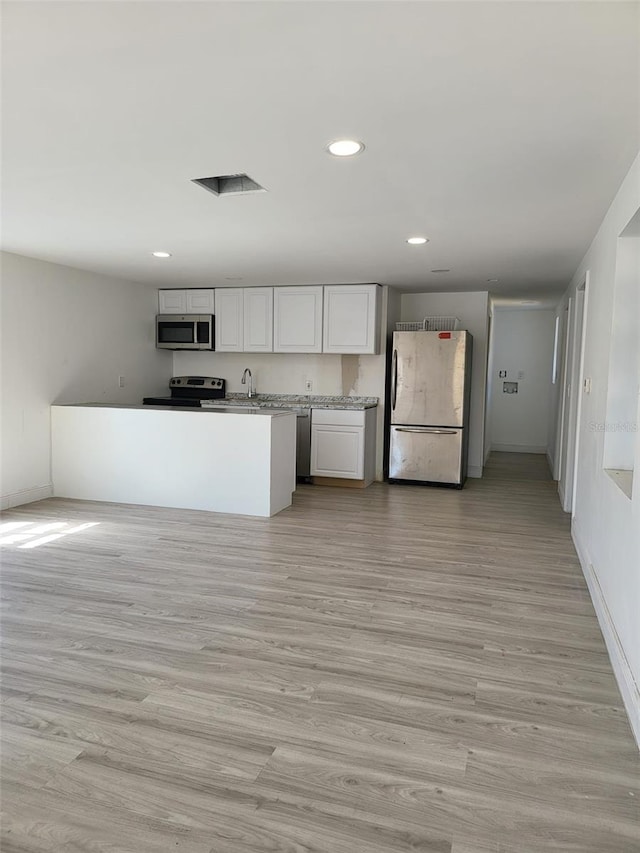 kitchen with stainless steel appliances, recessed lighting, white cabinets, and light wood-style floors