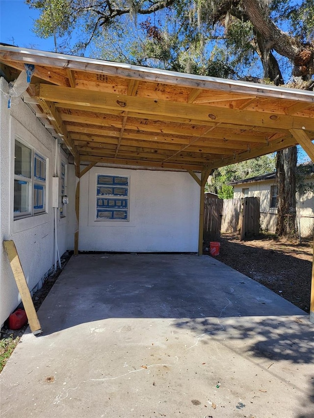 view of car parking with fence, an attached carport, and concrete driveway