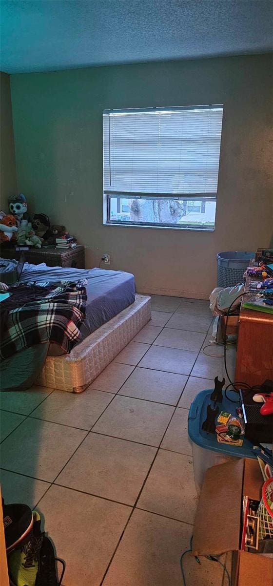 bedroom with multiple windows, a textured ceiling, and tile patterned floors