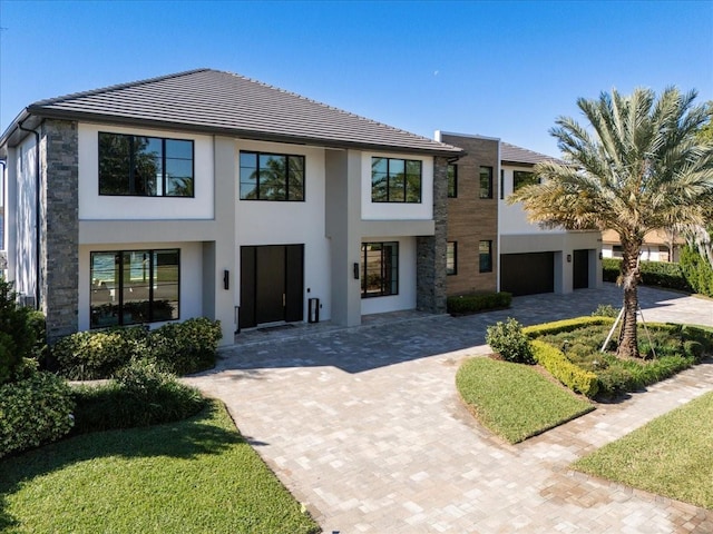 view of front facade featuring stone siding, driveway, and stucco siding