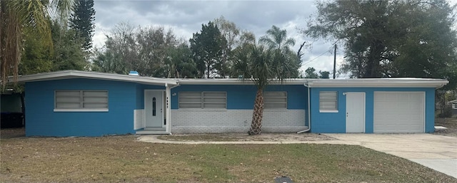 ranch-style home featuring a garage, concrete block siding, and driveway