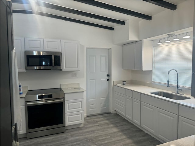 kitchen with beam ceiling, stainless steel appliances, a sink, and light countertops