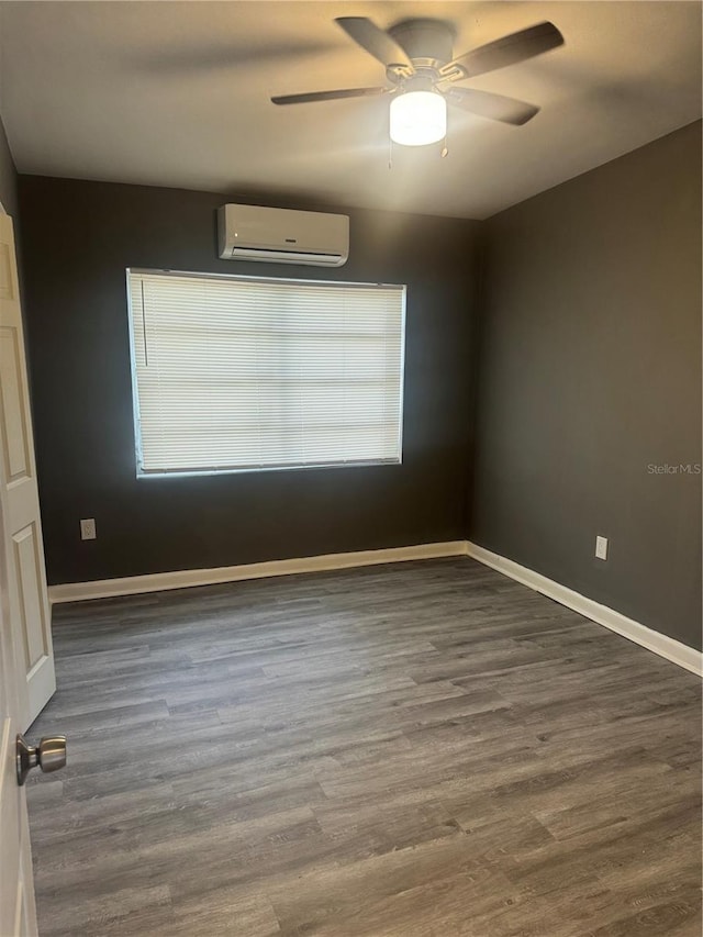 spare room with a ceiling fan, baseboards, an AC wall unit, and wood finished floors